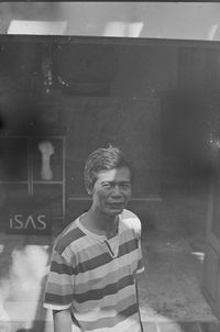 Portrait of young man looking through window