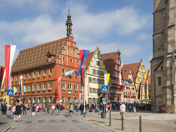 People on city street by buildings against sky