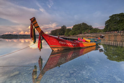 Fishing boat moored in lake against sky