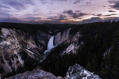 Scenic view of waterfall against sky during sunset