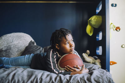 Girl with basketball day dreaming in bedroom
