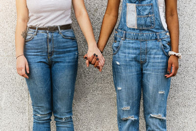 Midsection of female friends standing against wall