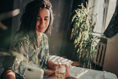 Young woman using phone while sitting on table