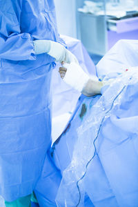 Midsection of doctor wrapping bandage on patient foot in hospital ward