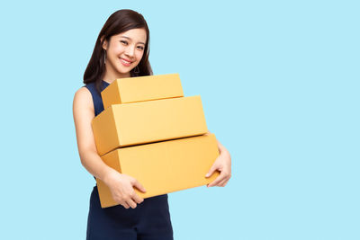 Portrait of a smiling young woman against blue background