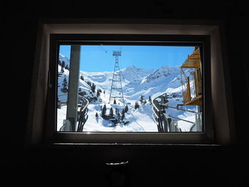 Tower on snow covered mountain seen through glass window