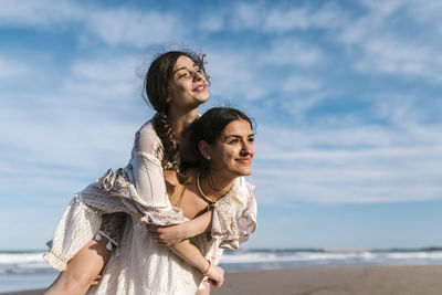 Portrait of smiling young woman on beach against sky