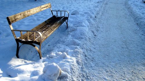 High angle view of wooden bench on snow covered field