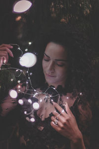 Close-up of beautiful woman holding illuminated lights