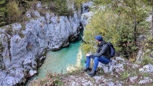 Woman sitting on rock by river in forest