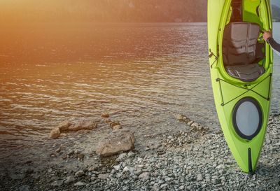 Cropped image of men holding kayak at riverbank