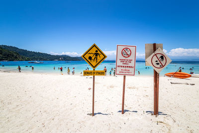 Information sign on beach against clear blue sky