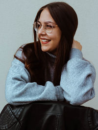 Portrait of beautiful young woman sitting against wall