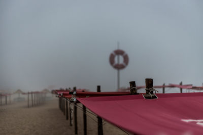 Empty seats on table by sea against sky