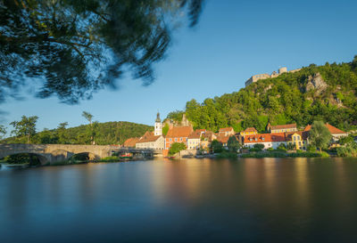 Scenic view of river by buildings against sky