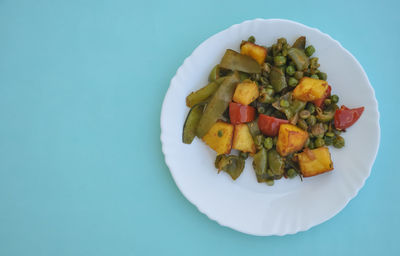 Photo of matar paneer mix veg on white plate isolated over light blue background