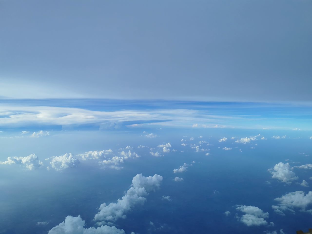 sky, cloud, horizon, aerial view, blue, nature, environment, cloudscape, scenics - nature, beauty in nature, atmosphere, copy space, no people, airplane, high up, tranquility, idyllic, outdoors, travel, plain, landscape, air vehicle, flying, day, backgrounds, tranquil scene, overcast, above, space, high angle view, white, urban skyline, wind, clear sky, water, fluffy, sunlight, planet earth, transportation