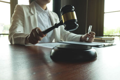 Midsection of judge with gavel and papers sitting at table