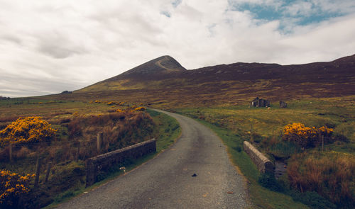 Road leading towards mountains against sky