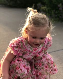 Smiling cute girl crouching on footpath