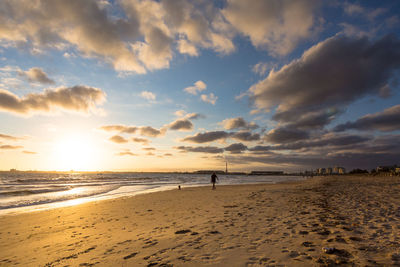 Scenic view of beach against sky at sunset