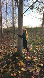 Portrait of young woman with autumn leaves on tree