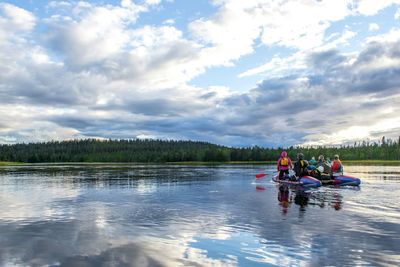 People kayaking in lake against sky