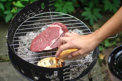 Close-up of person preparing food on barbecue grill