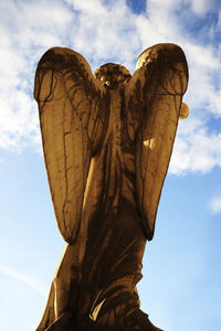 Low angle view of old angel statue against sky