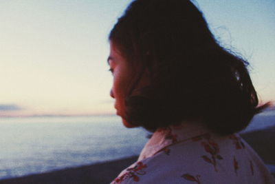 Close-up of man at beach against sky during sunset