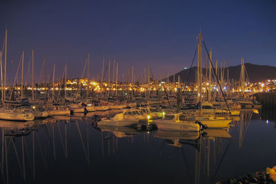 Boats moored in calm sea at night