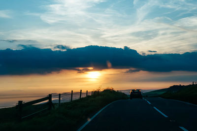 Car on road against sky during sunset