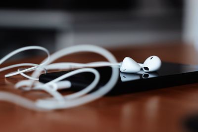 Close-up of in-ear headphones and mobile phone on table