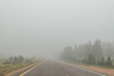 Road by trees against sky