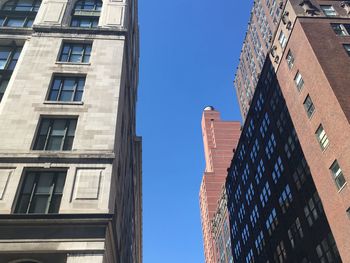 Low angle view of buildings in city against clear blue sky