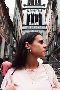 Young woman looking away against buildings in city