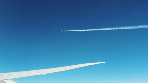 Low angle view of airplane flying against clear blue sky