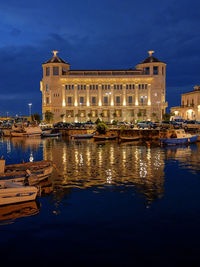 Buildings by river against sky