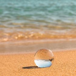 Close-up of crystal ball on beach