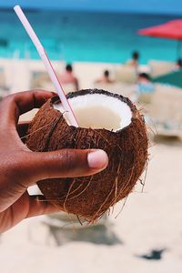 Close-up of hand holding coconut at beach