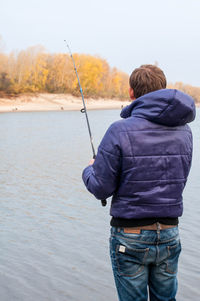 Rear view of man fishing against sea