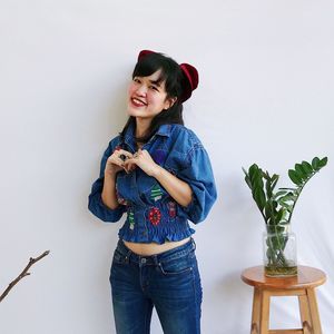 Young woman looking away while standing against plants
