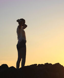 Man standing on rock on field against clear sky