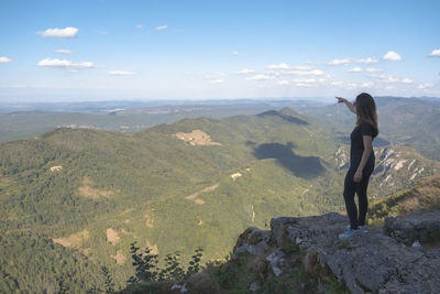 Rear view of man standing on mountain against sky