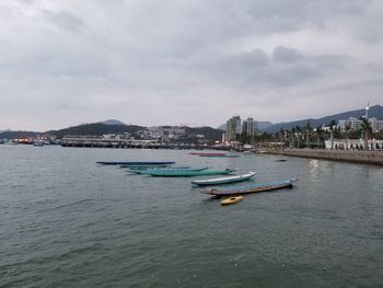 Nautical vessel moored on sea by buildings against sky