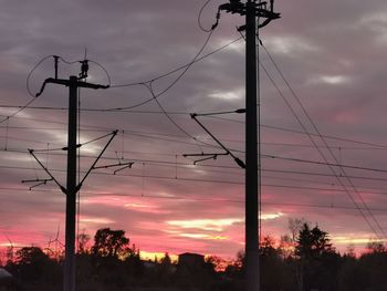 Low angle view of silhouette electricity pylon against sky during sunset