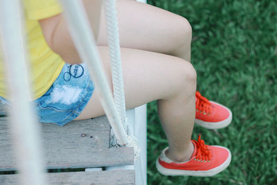 Low section of woman sitting on footbridge