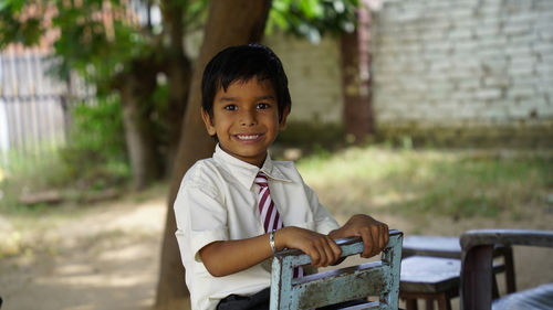 Portrait of happy cheerful indian school child or kids in uniform raising hand in the classroom