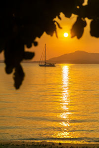 Silhouette sailboat in sea against sky during sunset