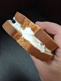 Close-up of hand holding ice cream cone against black background